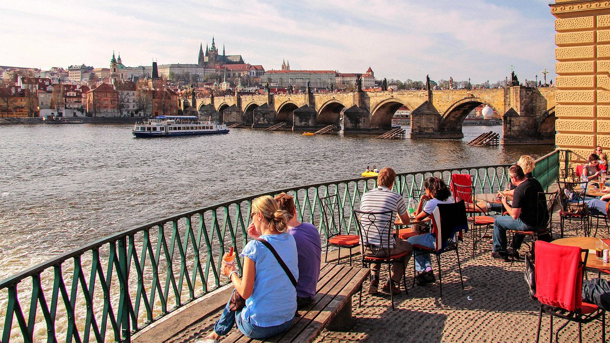 A street-side café with an outdoor seating area, where people are enjoying trdelník and coffee.