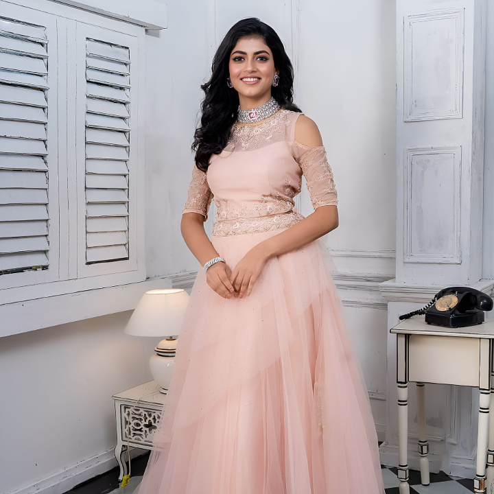 Aiswariya Sinha stands elegantly in a soft pink gown, surrounded by a refined, minimalist setting. Her poised stance and accessories reflect professionalism and growth, embodying the essence of presence in the modelling world.