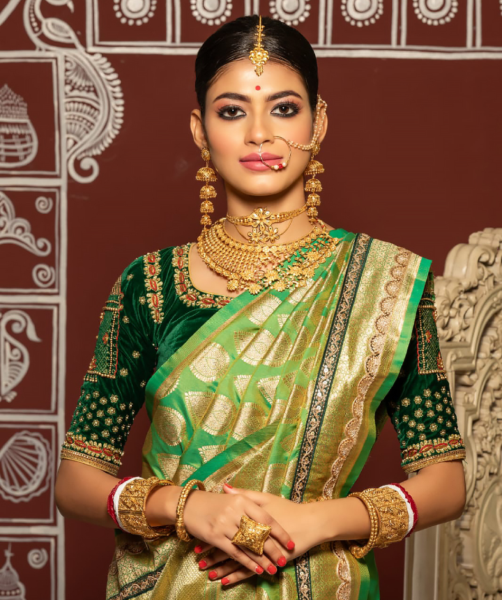 Aiswariya Sinha in a green and gold saree, adorned with intricate jewelry, seated in an ornate setting, reflecting on the perseverance behind her modelling journey.
