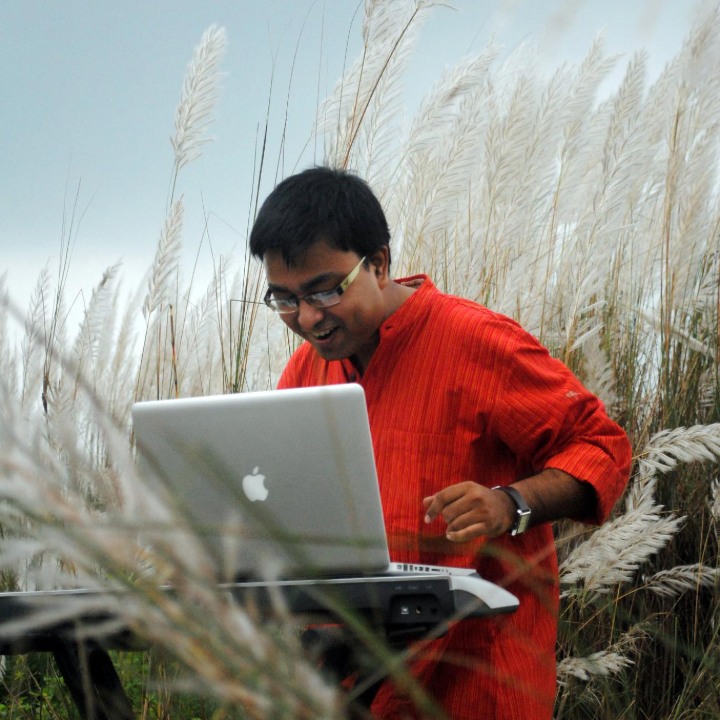 Drono Acharya composing music on a Mac keyboard—crafting sound beyond awards and recognition.