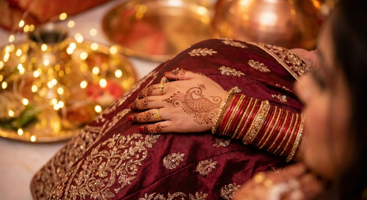 Close-up of bride’s hand with peacock mehndi, maroon lehenga and gold bangles – shot by Ranjan Bhattacharya